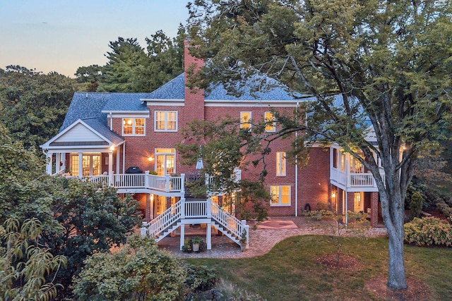 rear view of house with brick siding, a lawn, and stairway