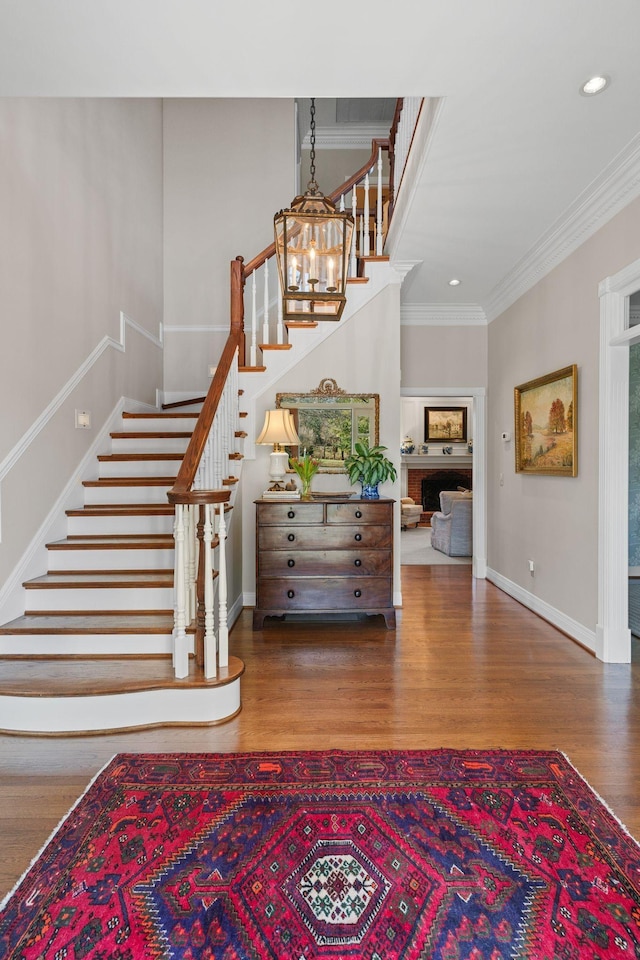 stairway with wood finished floors, ornamental molding, baseboards, and recessed lighting