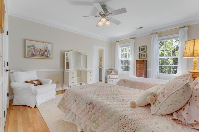 bedroom featuring ornamental molding, light wood-style floors, and a ceiling fan