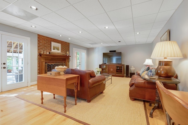 living room with a fireplace, wood finished floors, recessed lighting, and a paneled ceiling