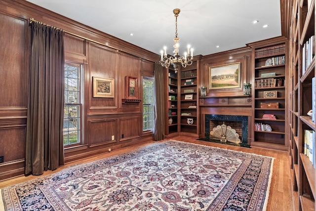 living area featuring a chandelier, a fireplace, healthy amount of natural light, light wood-type flooring, and crown molding