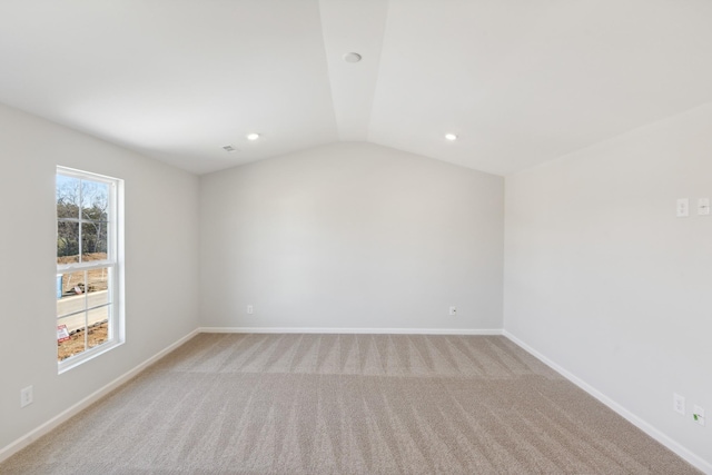 empty room featuring light carpet, recessed lighting, lofted ceiling, and baseboards