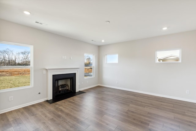 unfurnished living room featuring a fireplace with flush hearth, wood finished floors, baseboards, and recessed lighting