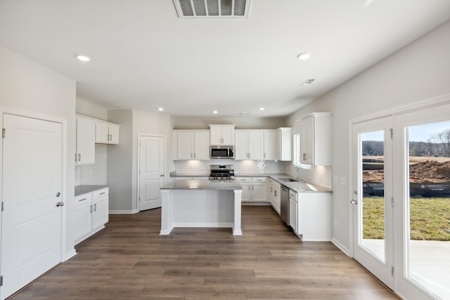 kitchen featuring stainless steel appliances, a sink, decorative backsplash, wood finished floors, and recessed lighting