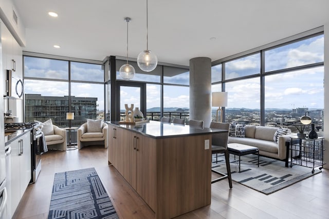 kitchen featuring modern cabinets, stainless steel appliances, dark countertops, a breakfast bar area, and floor to ceiling windows