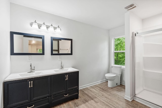 full bath featuring wood finished floors, a shower stall, toilet, and baseboards