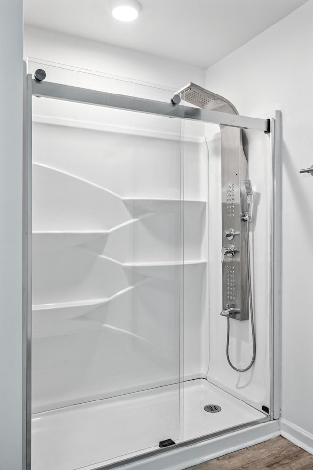 full bath featuring a stall shower and wood finished floors
