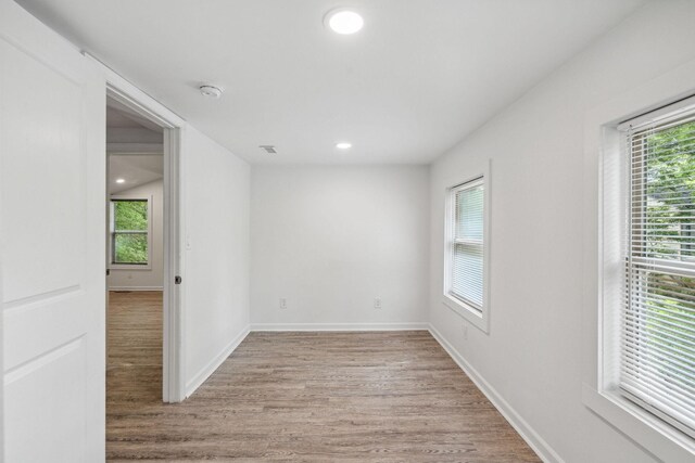 unfurnished room with light wood-style flooring, a smoke detector, plenty of natural light, baseboards, and recessed lighting