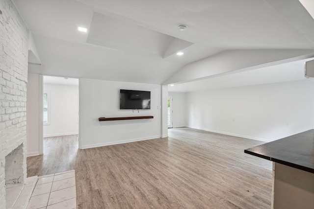 unfurnished living room with lofted ceiling, light wood-style flooring, healthy amount of natural light, and a fireplace