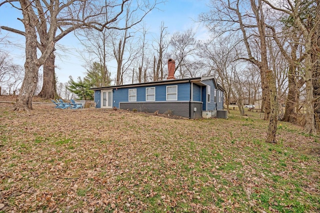 view of side of home with a chimney and central AC