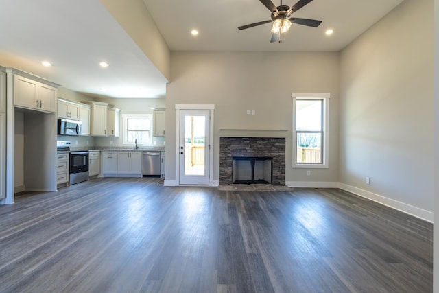 1161 Goose Dr, Springfield, TN 37172 - unfurnished living room with baseboards, dark wood-style floors, a ceiling fan, a sink, and a stone fireplace