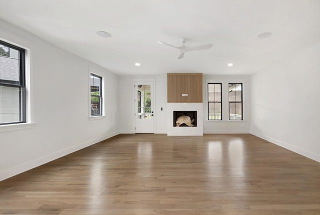 unfurnished living room featuring a ceiling fan, baseboards, a high end fireplace, wood finished floors, and recessed lighting