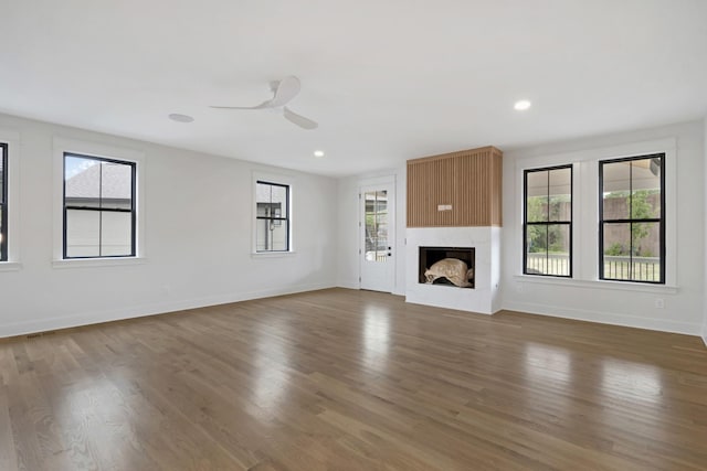 unfurnished living room featuring healthy amount of natural light, wood finished floors, a ceiling fan, baseboards, and recessed lighting