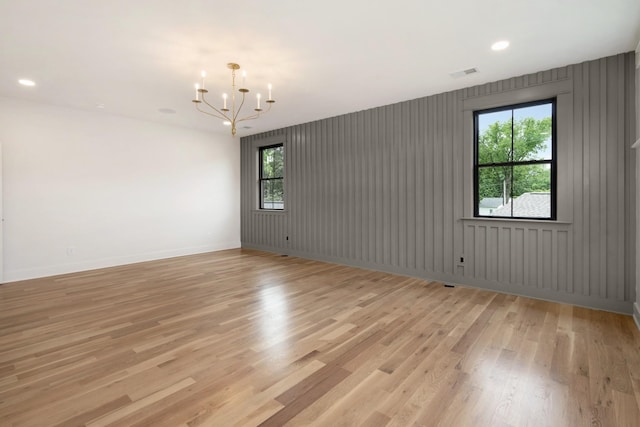 empty room featuring a chandelier, plenty of natural light, light wood-style floors, recessed lighting, and baseboards