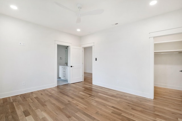 unfurnished bedroom with recessed lighting, light wood-style floors, baseboards, and a spacious closet