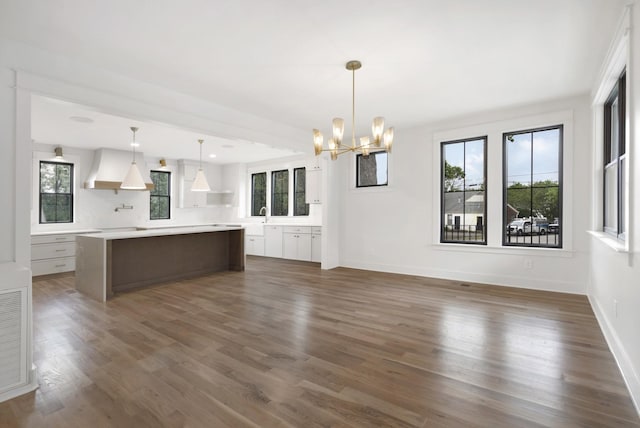 kitchen featuring custom range hood, a chandelier, light countertops, a center island, and dark wood-type flooring