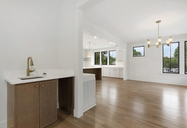 bar area with a sink, wood finished floors, a chandelier, and pendant lighting