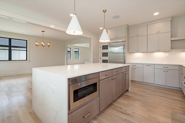 kitchen with open shelves, built in appliances, light wood-style flooring, hanging light fixtures, and a kitchen island