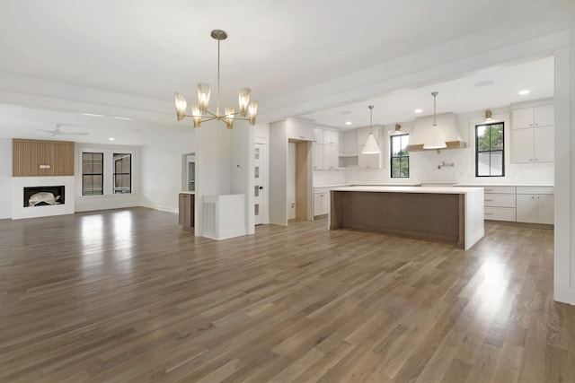 unfurnished living room with wood finished floors, a chandelier, recessed lighting, a ceiling fan, and a fireplace