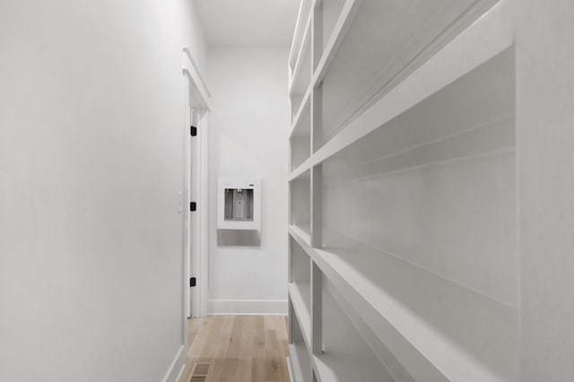 corridor with light wood-type flooring and baseboards