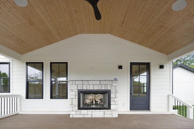 wooden terrace featuring ceiling fan and an outdoor stone fireplace