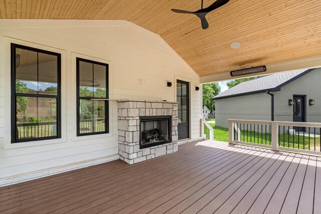 wooden deck featuring an outdoor stone fireplace and ceiling fan
