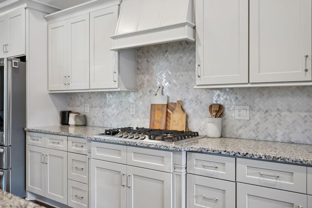 1567 Bunbury Dr, Thompsons Station, TN 37179 - kitchen featuring appliances with stainless steel finishes, premium range hood, decorative backsplash, and light stone countertops