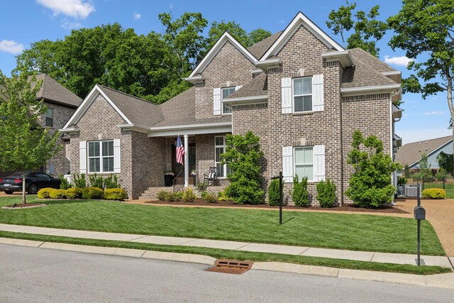 1567 Bunbury Dr, Thompsons Station, TN 37179 - view of front facade with a shingled roof, brick siding, a front lawn, and central air condition unit
