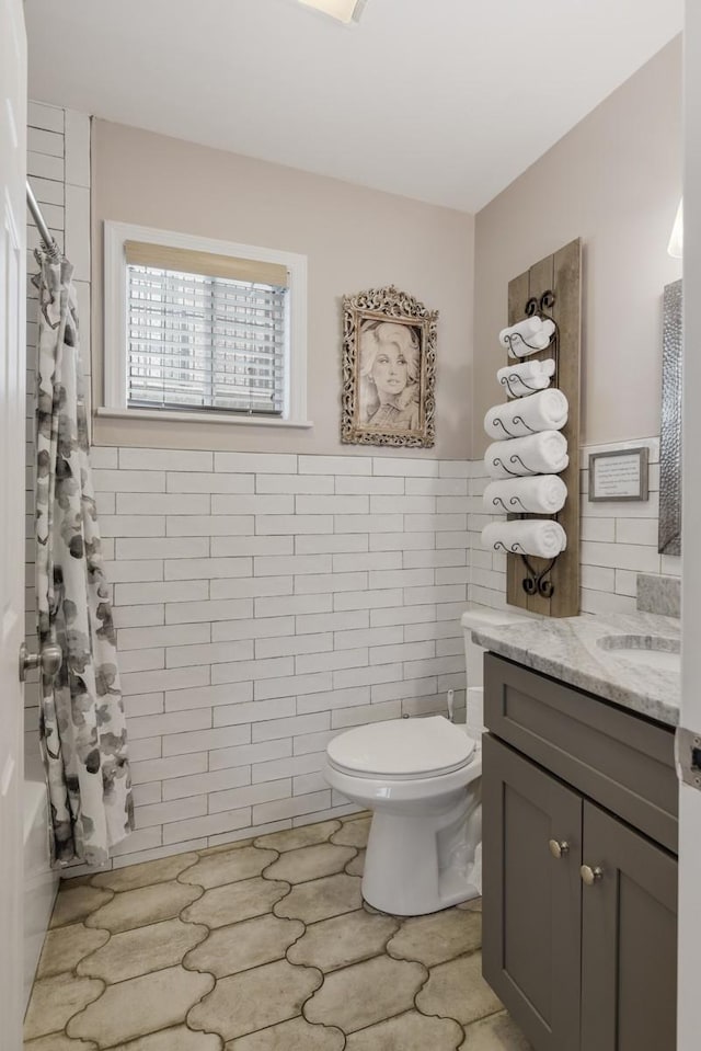 bathroom featuring tile walls, toilet, vanity, a shower with curtain, and a wainscoted wall
