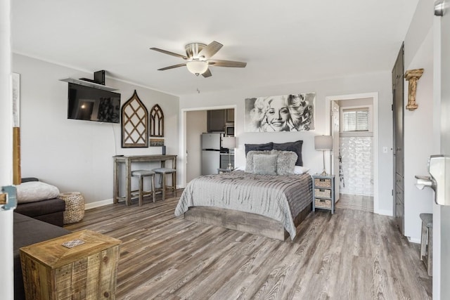 bedroom with wood finished floors, freestanding refrigerator, baseboards, and ceiling fan