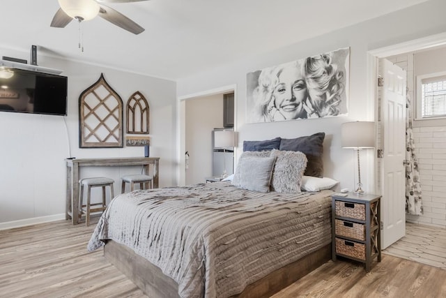 bedroom featuring wood finished floors, ceiling fan, baseboards, and ensuite bathroom