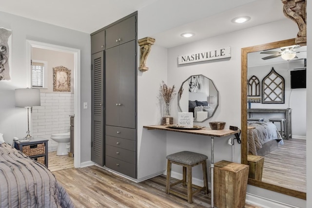 bedroom with wood finished floors, ensuite bathroom, a closet, and tile walls