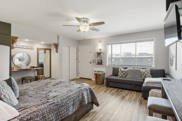 bedroom with light wood-style floors, ceiling fan, and a closet