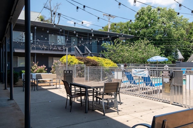 view of patio with outdoor dining area, fence, and a community pool