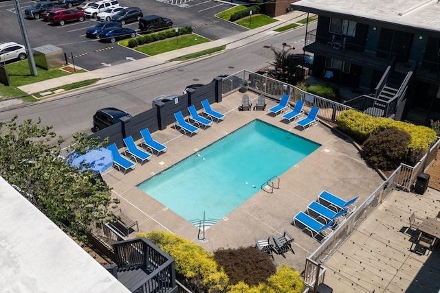 community pool with fence, a patio area, and stairway