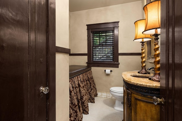 bathroom with toilet, vanity, and tile patterned flooring