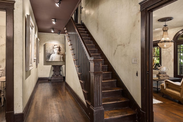 stairs featuring wood-type flooring, a chandelier, and baseboards