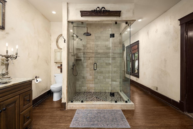 full bath with wood finished floors, a shower stall, toilet, baseboards, and vanity