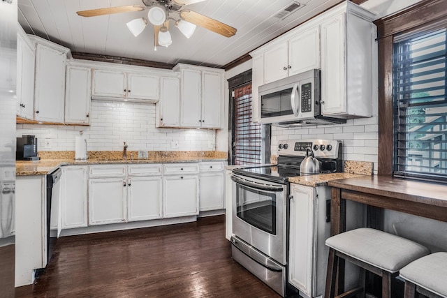 kitchen featuring stainless steel appliances, a sink, a ceiling fan, white cabinetry, and backsplash