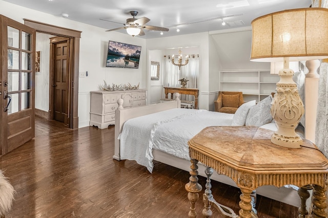 bedroom featuring wood finished floors, track lighting, and a chandelier
