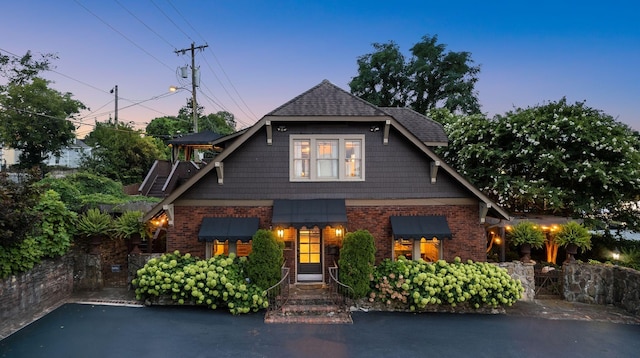 craftsman inspired home with brick siding and roof with shingles