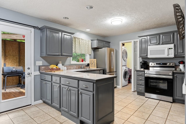 1056 Simms Heights Rd, Kingston Springs, TN 37082 - kitchen featuring stainless steel appliances, stacked washer / dryer, gray cabinets, light tile patterned flooring, and a textured ceiling