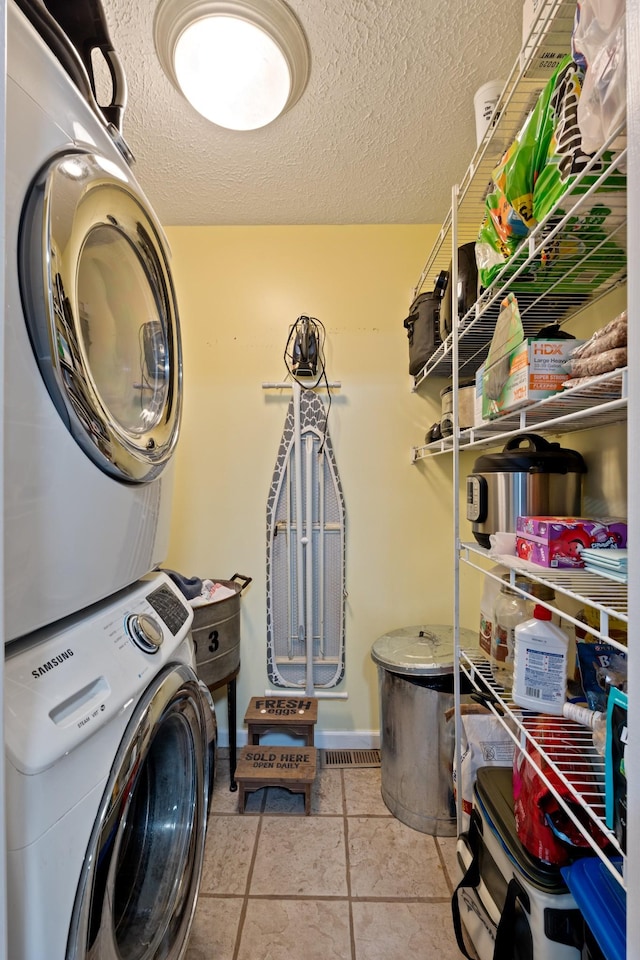1056 Simms Heights Rd, Kingston Springs, TN 37082 - laundry area featuring estacked washer and dryer, a textured ceiling, tile patterned floors, and baseboards