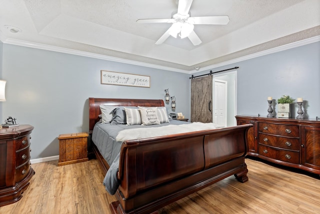 1056 Simms Heights Rd, Kingston Springs, TN 37082 - bedroom featuring a raised ceiling, light wood-style floors, a barn door, a ceiling fan, and ornamental molding