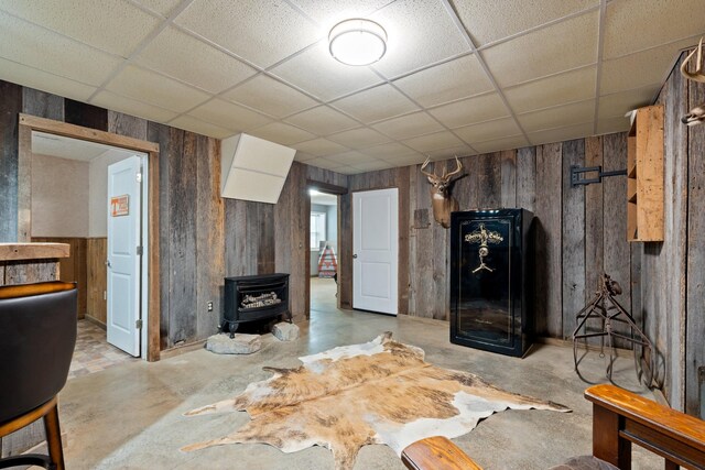 1056 Simms Heights Rd, Kingston Springs, TN 37082 - living area with a wood stove, a drop ceiling, wood walls, and unfinished concrete flooring