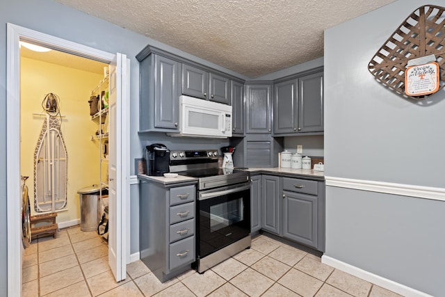1056 Simms Heights Rd, Kingston Springs, TN 37082 - kitchen featuring white microwave, stainless steel electric range, gray cabinetry, light tile patterned floors, and a textured ceiling