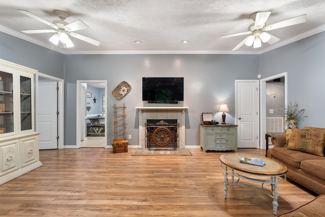 1056 Simms Heights Rd, Kingston Springs, TN 37082 - living area featuring ceiling fan, light wood finished floors, a tile fireplace, a textured ceiling, and ornamental molding