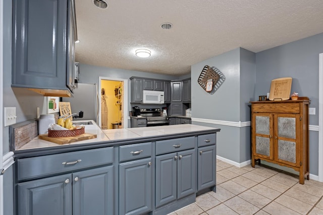 1056 Simms Heights Rd, Kingston Springs, TN 37082 - kitchen featuring stainless steel appliances, a peninsula, a textured ceiling, a sink, and baseboards