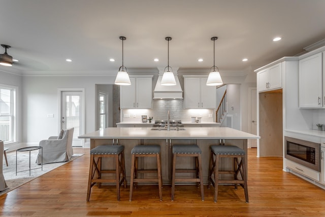 2212 Peterson Dr, Chattanooga, TN 37421 - kitchen featuring stainless steel microwave, decorative backsplash, light countertops, a center island with sink, and crown molding