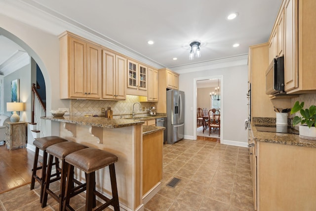 2335 Garrison Cv, Murfreesboro, TN 37130 - kitchen featuring stainless steel appliances, a peninsula, a kitchen bar, a sink, and backsplash